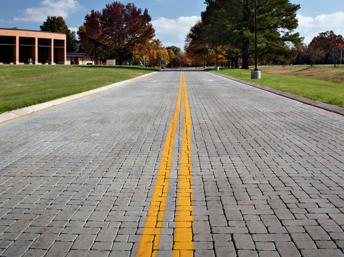 Interlocking concrete paver roadway with solid yellow lines in the center, using pavers with a thickness of 4”, aspect ratio of 3:1.