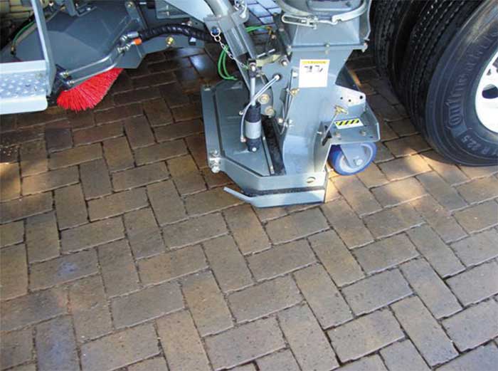 Street sweeper truck cleaning interlocking concrete pavers.