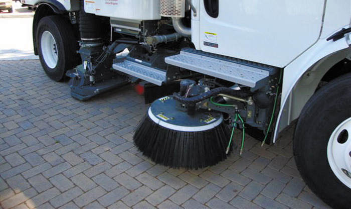 Street sweeper truck cleaning interlocking concrete pavers.