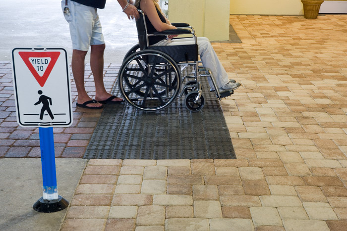 Person in a wheelchair going over a concrete paver surface using Moduline Truncated Dome Pavers.